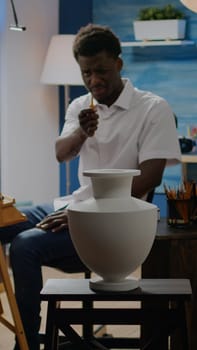 Artist of african american ethnicity analyzing vase