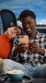 Joyful interracial couple taking selfies with smartphone