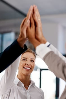 Heres to scoring many successes together. a group of businesspeople high fiving together in an office.