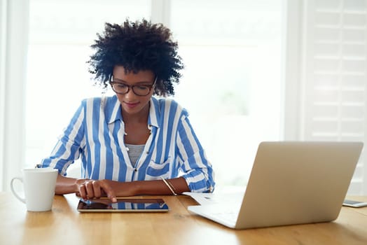She values the independence of working from home. a young woman working on her digital tablet and laptop at home.