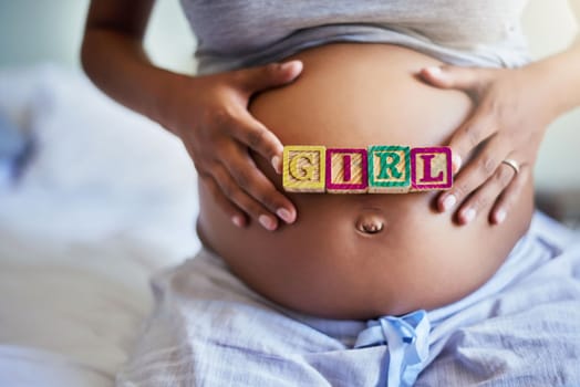 My princess is almost here. a pregnant woman with wooden blocks on her belly that spell the word girl.