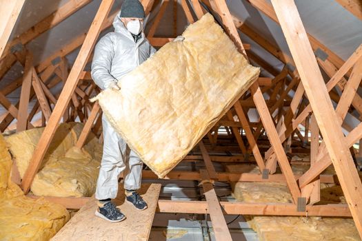 a worker in protective overalls works with glass wool