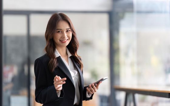 Happy businesswoman holding telephone working standing in office using mobile cell phone working