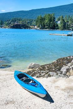 Blue lightweight canoe boat on a shore of Pacific ocean bay on sunny day
