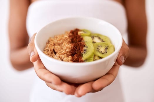 A healthy breakfast will get you through the day. Studio shot of an unrecognizable woman holding a bowl with oats and kiwi fruit.