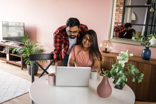 technology remote job and lifestyle concept - happy indian man and woman in glasses with laptop computer working at home office