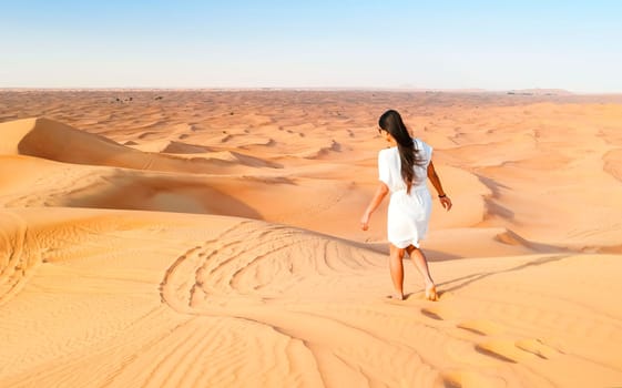Young Asian woman walking in the desert, Sand dunes of Dubai United Arab Emirates,