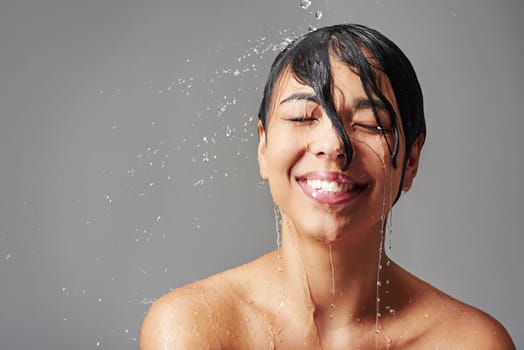 Take a shower and feel reinvigorated. Studio shot of a young woman enjoying a shower against a gray background.