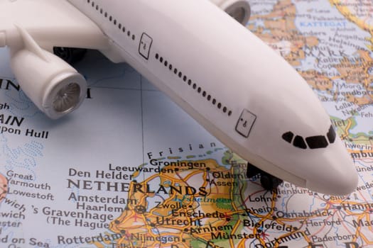 Close up of a miniature passenger plane on a colorful map showing Amsterdam, Netherlands through selective focus, background blur