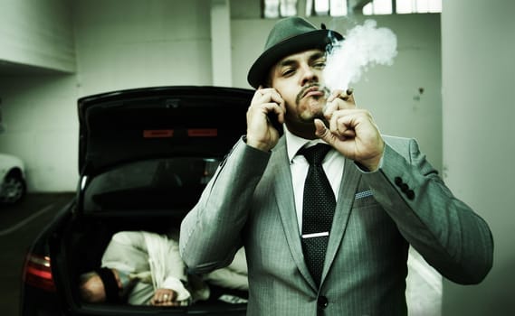Celebratory cigar. An arrogant mobster blowing smoke into the air while talking on his cellphone following a successful abduction.