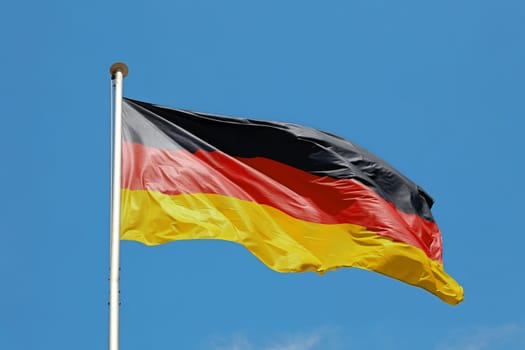 German flag waving in cloudy blue sky