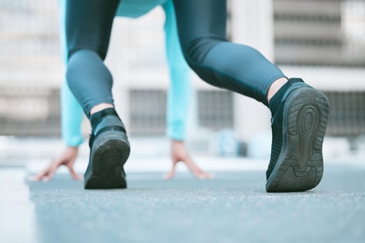 Closeup of sole of shoes of one female athlete preparing to run a race in starting position while exercising outdoors. Sporty woman wearing footwear for sprint cardio training