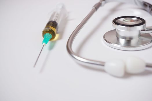 syringe, stethoscope and pills on a white doctor's gown