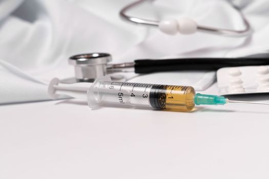syringe, stethoscope and pills on a white doctor's gown