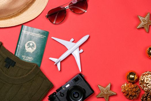 Preparation for travel concept - passport, camera, hat, airplane, chrismas decorations on red background