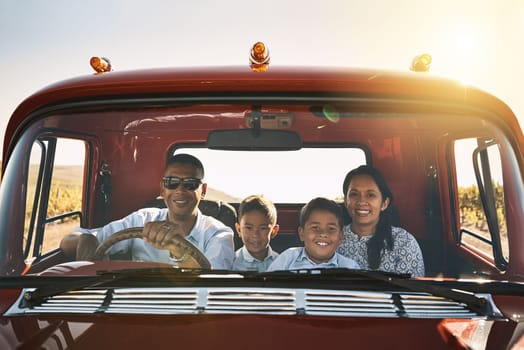 Making the best of the adventure. a cheerful young family driving in a red pickup truck on a rural road outside.