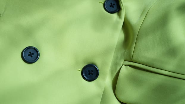 Closeup of custom made green jacket with black buttons