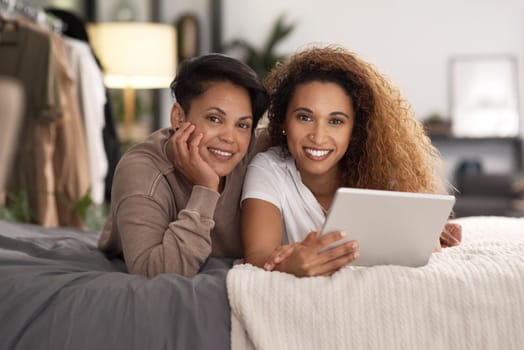 She was beautiful for that sparkle in her eyes. a young lesbian couple using a tablet while relaxing in their bedroom.