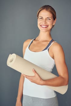 Get back on your mat. a woman holding her yoga mat against a grey background.