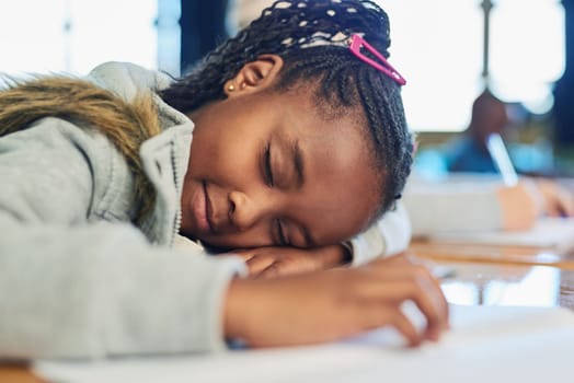 Her little brain can only carry so much. an elementary school girl sleeping on her desk in class.