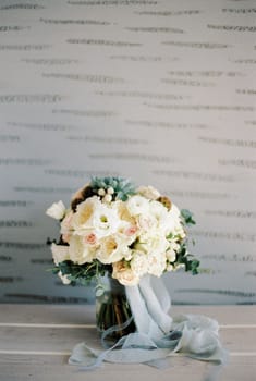 Bridal bouquet stands on the table against the background of the wall