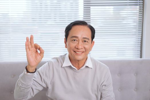 Asian senior man gesture hands ok sign.