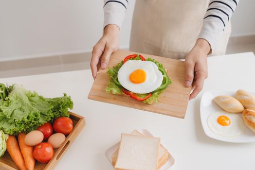 Hands of man prepare breakfast with sandwich with poached eggs