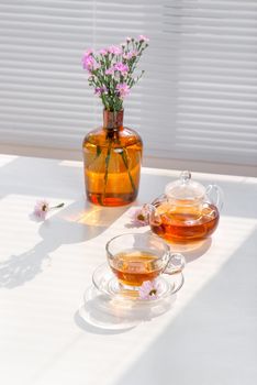 Cup of tea, teapot and vase on the table