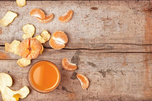 Citrus juice in glass and fresh mandarin orange on wooden background