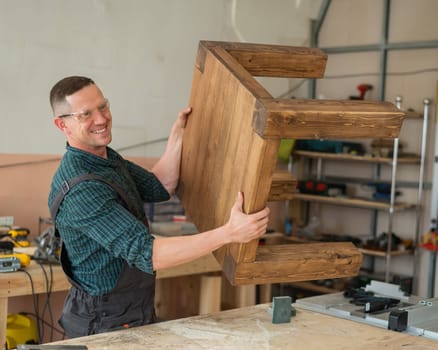 Male carpenter finishing work on wooden table in workshop.