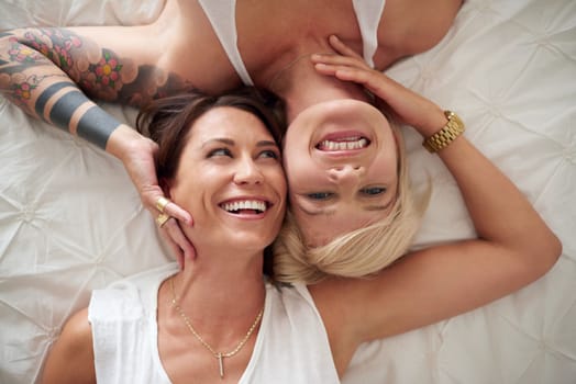 Laughter and love. High angle shot of a loving lesbian couple lying in bed.