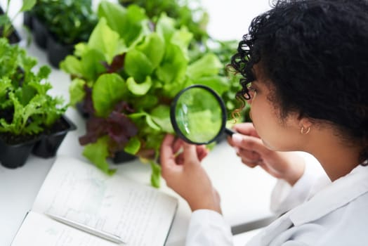 Its a profession for nature lovers. a female scientist looking at a plant through a magnifying glass.
