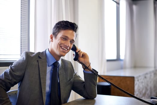 Hes built up a great reputation for himself. a handsome young businessman talking on the phone while sitting at his desk.