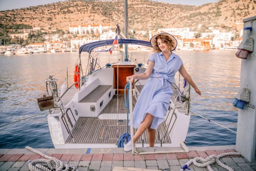 Woman yacht sea. A young happy woman in a blue dress and hat sta