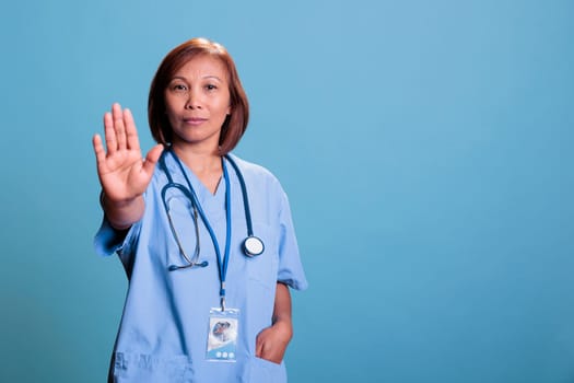 Asian medical assistant doing stop gesture with hands while working at illness expertise