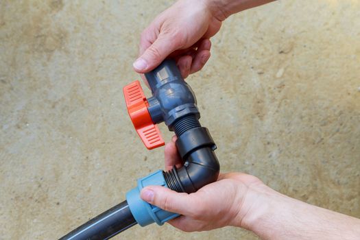 A plumber installs a ball valve for water on a polyethylene pipe. Installation of irrigation system.