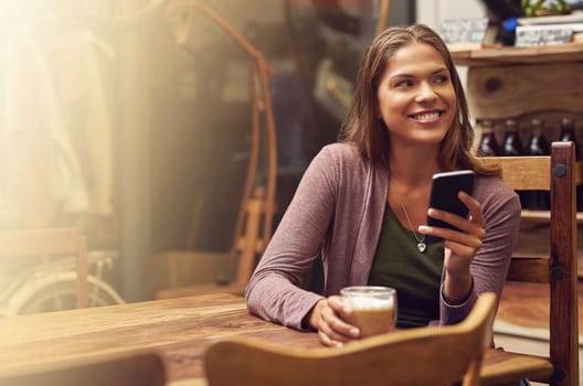 Instant connection, instant happiness. a young woman using her phone in a cafe.