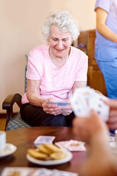 She picked up a good hand. seniors playing cards in their retirement home.