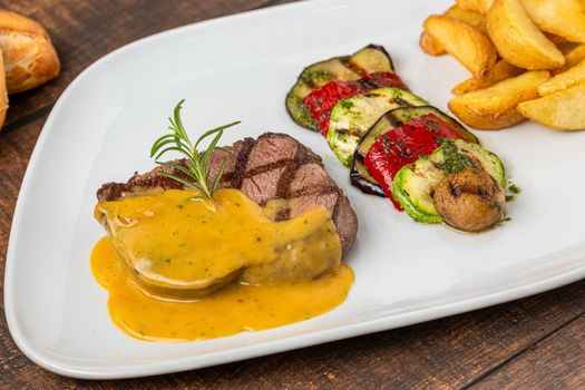 Grilled beef tenderloin with grilled vegetables on a white porcelain plate