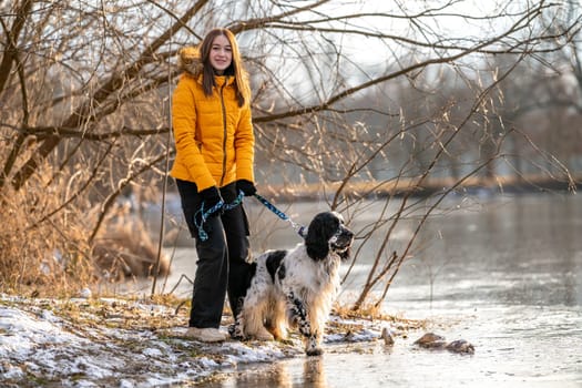 a girl with a dog by a frozen lake. english setter