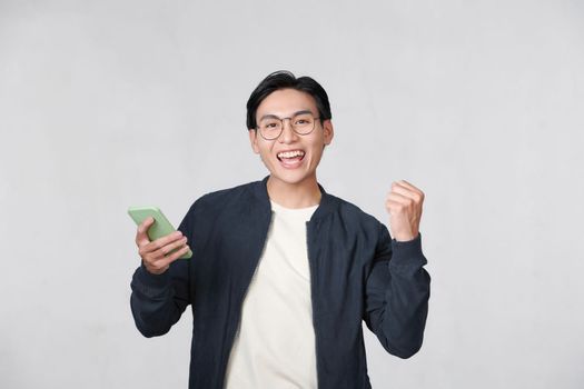 Happy man holding smartphone and celebrating his success over white background