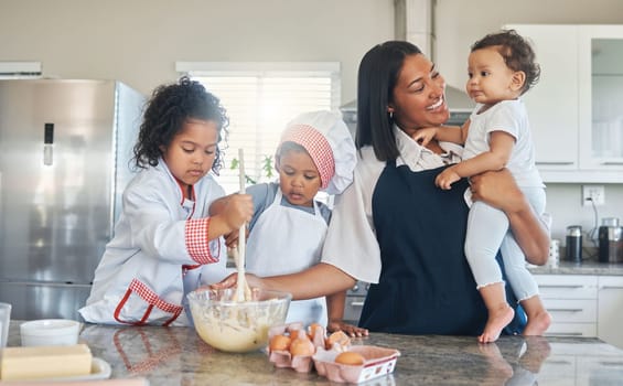 Were making some pancakes in celebration of that new tooth. a mother holding her baby while baking with her two children