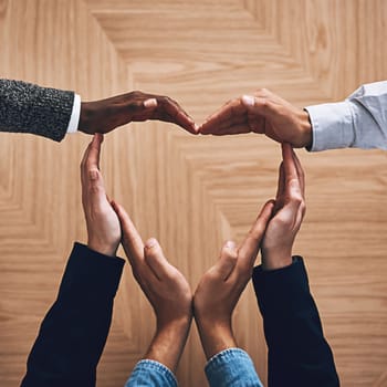 Its what makes the world go round. High angle shot of a group of unidentifiable businesspeople forming a heart shape with their hands.