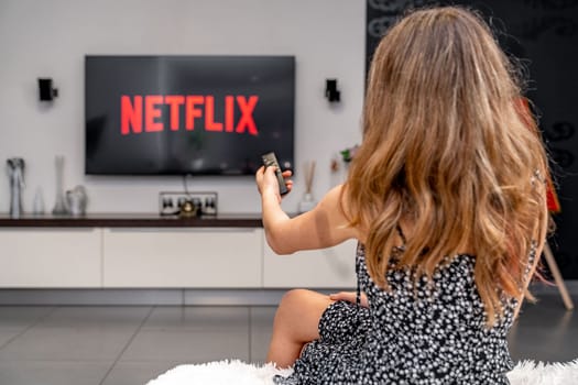 Olomouc, Czech Republic - February 10, 2023: teenager turned on netflix on tv with remote control