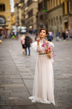 a bride in a wedding dress with a Venetian mask in her hands in Florence.Italy