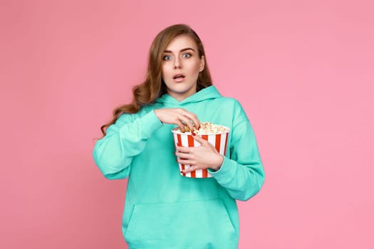 woman in sweatshirt holding bucket of popcorn