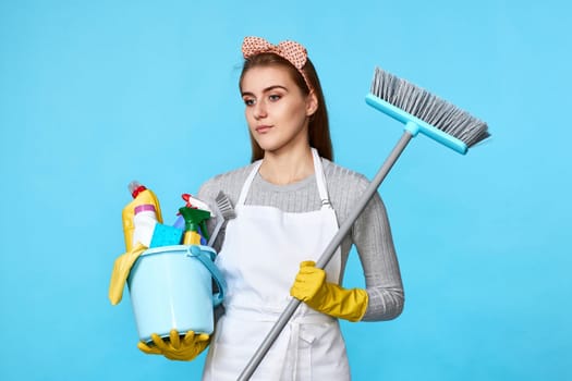 woman in gloves holding bucket of detergents and broom