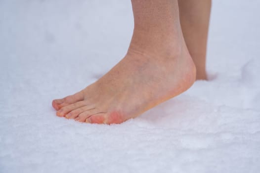 Close-up of a woman walking barefoot in the snow. Boosting immunity with cryotherapy.