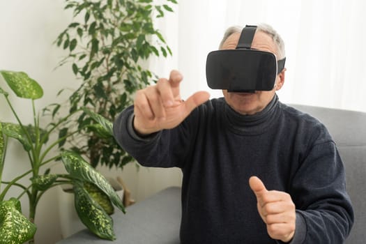 technology, augmented reality, gaming, entertainment and people concept - senior man with virtual headset or 3d glasses playing videogame at home.
