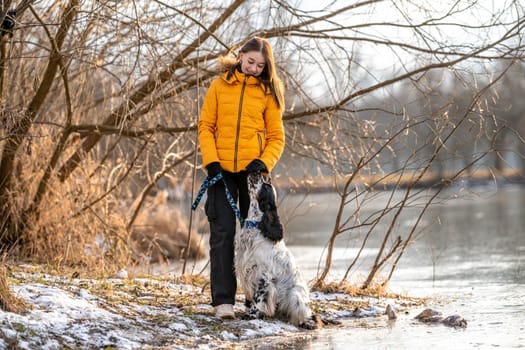 a girl with a dog by a frozen lake. english setter